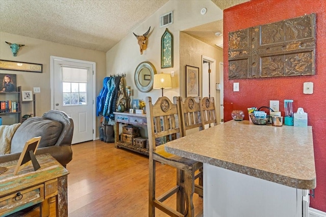 1320 Laredo Dr, Granbury, TX 76048 - dining space featuring a textured ceiling, wood finished floors, and vaulted ceiling