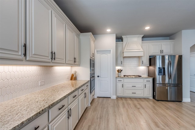 1421 Cedar Creek Dr, Anna, TX 75409 - kitchen featuring stainless steel appliances, tasteful backsplash, premium range hood, white cabinetry, and light wood-style flooring