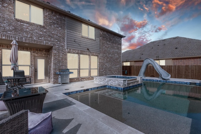 1421 Cedar Creek Dr, Anna, TX 75409 - pool at dusk with a water slide, a fenced backyard, a patio, and a pool with connected hot tub