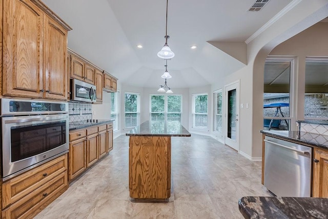 230 Mitchell Blvd, Weatherford, TX 76087 - kitchen with appliances with stainless steel finishes, tasteful backsplash, brown cabinets, decorative light fixtures, and a center island