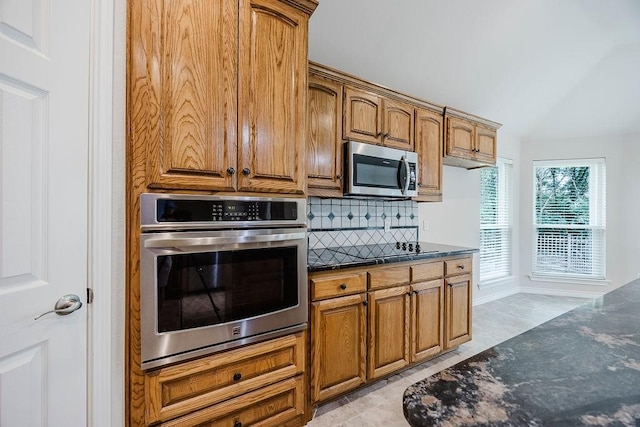 230 Mitchell Blvd, Weatherford, TX 76087 - kitchen featuring appliances with stainless steel finishes, backsplash, dark stone countertops, and brown cabinets