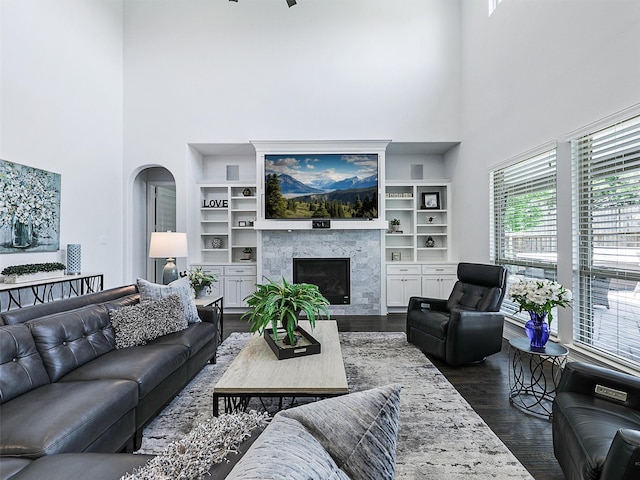 1551 Sweetwater Ln, Prosper, TX 75078 - living area featuring a towering ceiling, dark wood-style floors, a premium fireplace, arched walkways, and built in shelves
