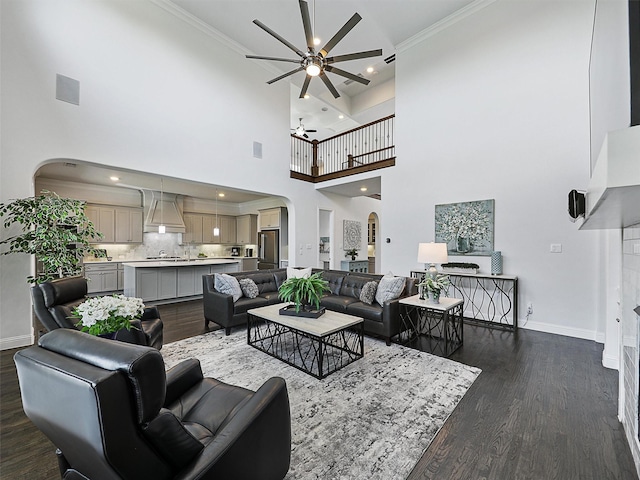 1551 Sweetwater Ln, Prosper, TX 75078 - living room featuring arched walkways, ceiling fan, dark wood-type flooring, a high ceiling, and crown molding