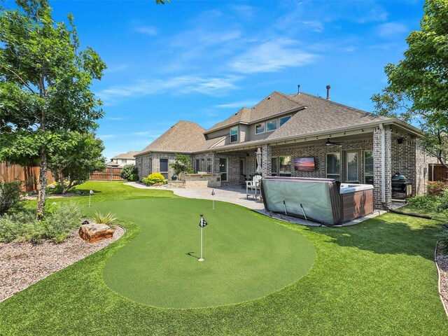 1551 Sweetwater Ln, Prosper, TX 75078 - rear view of property featuring a putting green, a patio, brick siding, roof with shingles, and a hot tub