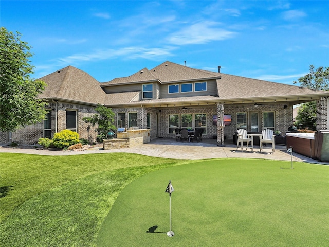 1551 Sweetwater Ln, Prosper, TX 75078 - rear view of property featuring a putting green, brick siding, a patio area, an outdoor kitchen, and roof with shingles