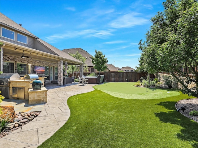 1551 Sweetwater Ln, Prosper, TX 75078 - fenced backyard with an outdoor kitchen, a putting area, a patio area, and ceiling fan