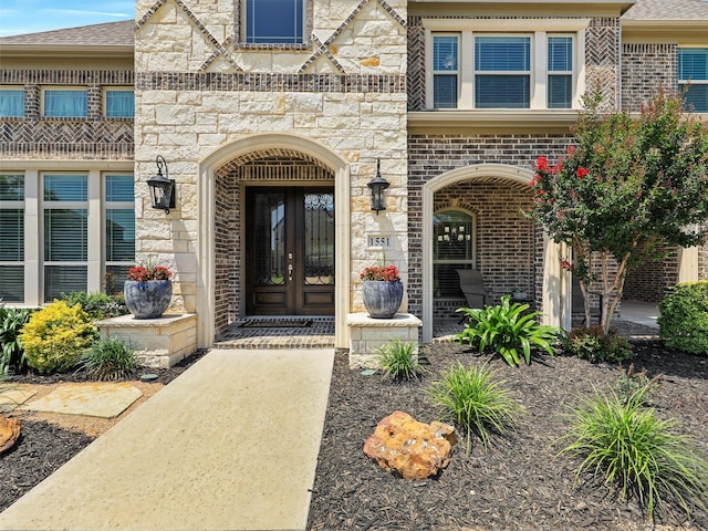1551 Sweetwater Ln, Prosper, TX 75078 - view of exterior entry featuring french doors, stone siding, brick siding, and roof with shingles