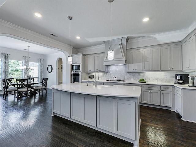 1551 Sweetwater Ln, Prosper, TX 75078 - kitchen featuring gray cabinets, arched walkways, appliances with stainless steel finishes, premium range hood, and light countertops