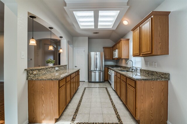 7806 Albany Dr, Rowlett, TX 75089 - kitchen with freestanding refrigerator, white microwave, brown cabinetry, and vaulted ceiling