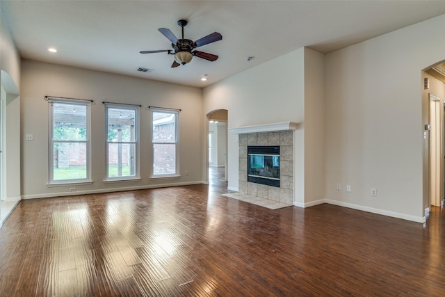 7806 Albany Dr, Rowlett, TX 75089 - unfurnished living room with arched walkways, a ceiling fan, wood finished floors, a tiled fireplace, and recessed lighting