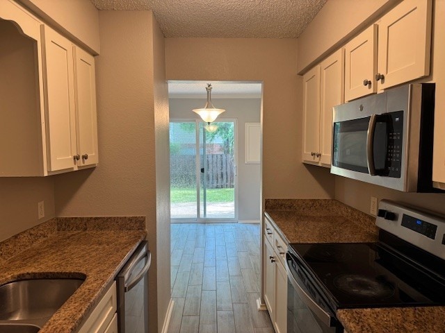 4024 Southern Charm Ct, Arlington, TX 76016 - kitchen with stainless steel appliances, white cabinets, light wood finished floors, a textured ceiling, and dark stone counters