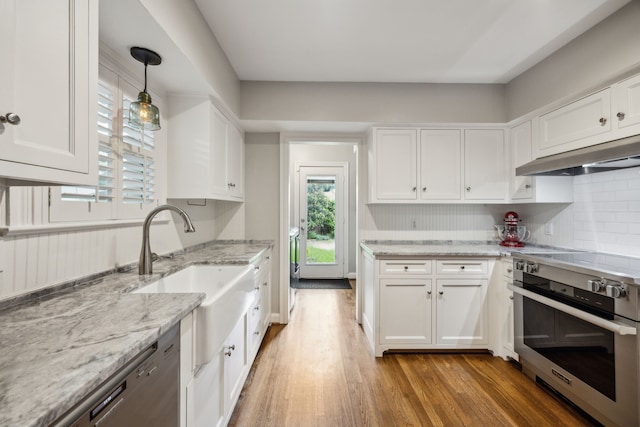 6443 Velasco Ave, Dallas, TX 75214 - kitchen with appliances with stainless steel finishes, wall chimney range hood, light wood-style floors, a sink, and white cabinets