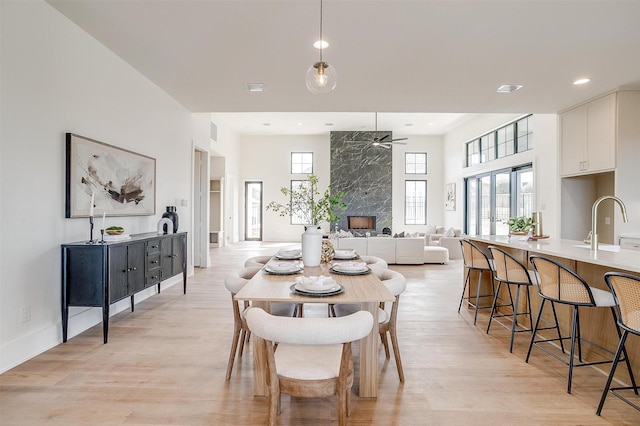 4513 Fair Creek Ter, Fort Worth, TX 76008 - dining area featuring light wood-style flooring, ceiling fan, a premium fireplace, recessed lighting, and a towering ceiling