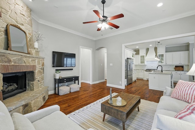 9008 Cypress Creek Rd, Lantana, TX 76226 - living room with dark wood-style floors, a stone fireplace, crown molding, a ceiling fan, and arched walkways
