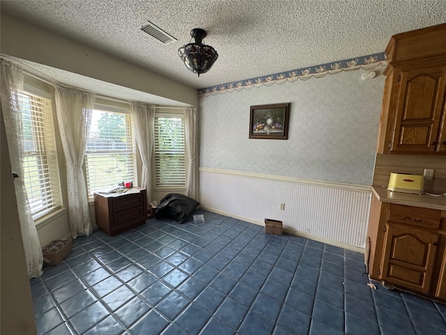 1402 Clarks Dr, Abilene, TX 79602 - unfurnished dining area featuring a wainscoted wall, a textured ceiling, and dark tile patterned floors