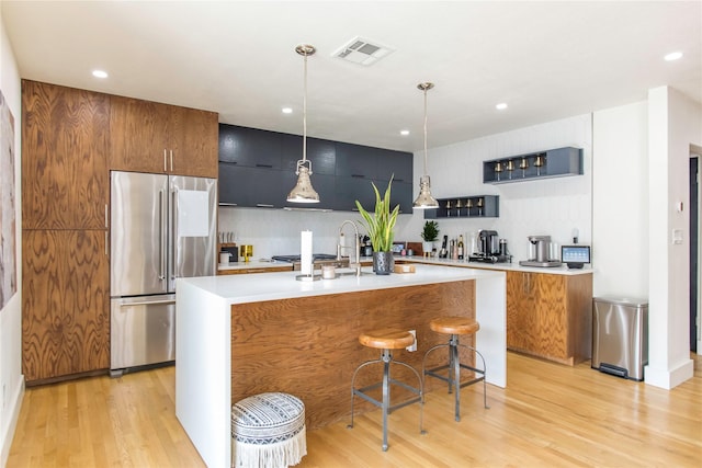 729 Bizerte Ave, Dallas, TX 75224 - kitchen with high end refrigerator, light countertops, light wood-style flooring, modern cabinets, and pendant lighting
