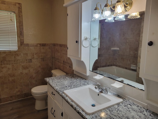 316 Charlie Dr, Whitesboro, TX 76273 - full bathroom featuring toilet, tile walls, vanity, a bathtub, and wood finished floors