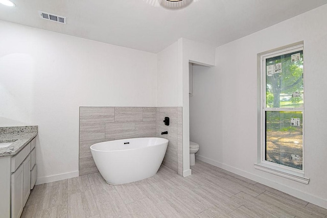 715 Pheasant Run, Burleson, TX 76028 - full bathroom with a freestanding bath, vanity, toilet, wood finished floors, and baseboards