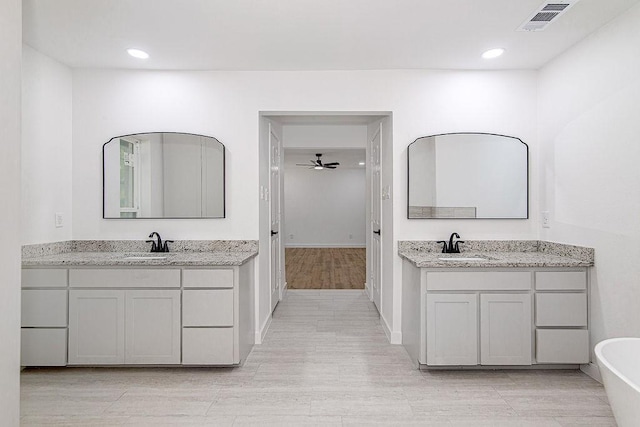 715 Pheasant Run, Burleson, TX 76028 - bathroom with two vanities, a soaking tub, wood finished floors, ceiling fan, and recessed lighting