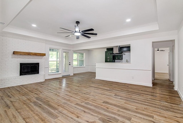 715 Pheasant Run, Burleson, TX 76028 - unfurnished living room featuring a raised ceiling, ceiling fan, wood finished floors, a brick fireplace, and crown molding