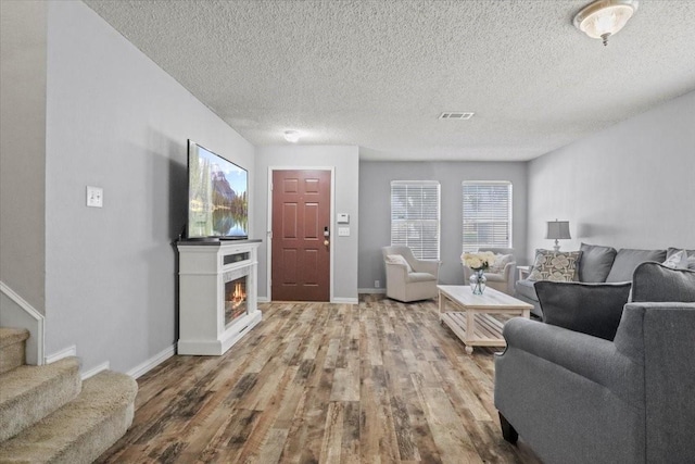 4325 Falcon Dr, Sherman, TX 75092 - living area featuring wood finished floors, baseboards, stairway, a textured ceiling, and a glass covered fireplace