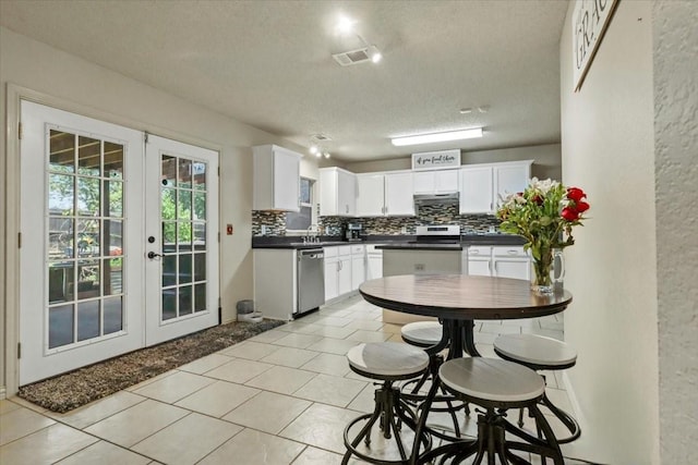 4325 Falcon Dr, Sherman, TX 75092 - kitchen with a textured ceiling, appliances with stainless steel finishes, dark countertops, decorative backsplash, and french doors