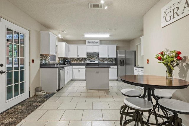 4325 Falcon Dr, Sherman, TX 75092 - kitchen featuring appliances with stainless steel finishes, dark countertops, decorative backsplash, a center island, and a textured ceiling