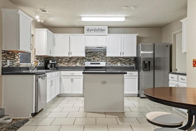 4325 Falcon Dr, Sherman, TX 75092 - kitchen with appliances with stainless steel finishes, under cabinet range hood, dark countertops, a center island, and a sink
