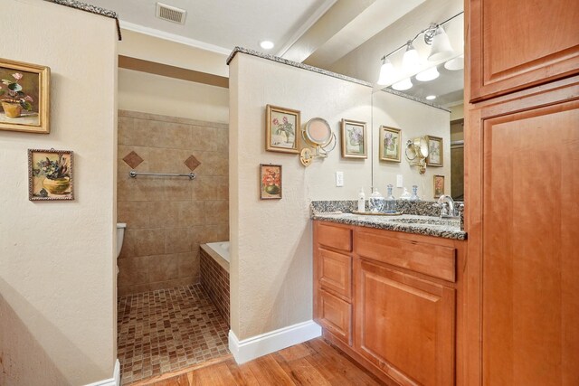 1125 Sayles Blvd, Abilene, TX 79605 - bathroom featuring double vanity, tiled shower, wood finished floors, baseboards, and crown molding