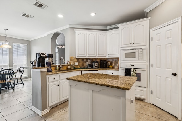 412 Kyle Ln, Lewisville, TX 75067 - kitchen featuring white appliances, a sink, crown molding, a kitchen island, and white cabinetry