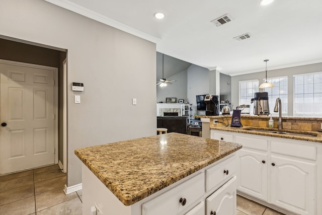 412 Kyle Ln, Lewisville, TX 75067 - kitchen featuring a sink, a ceiling fan, a fireplace, a kitchen island, and ornamental molding