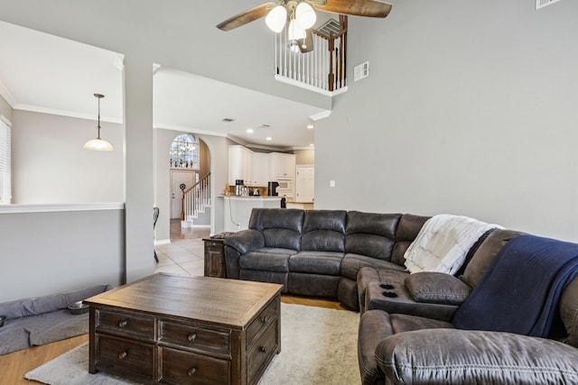 412 Kyle Ln, Lewisville, TX 75067 - living room with arched walkways, a ceiling fan, stairs, ornamental molding, and light wood-style flooring