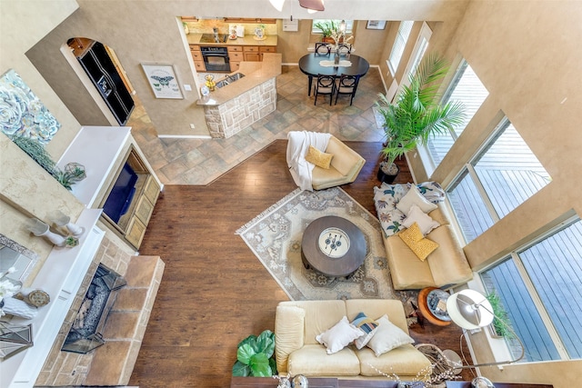 12744 Concho Dr, Frisco, TX 75033 - living area featuring wood finished floors, a towering ceiling, a fireplace, and a ceiling fan