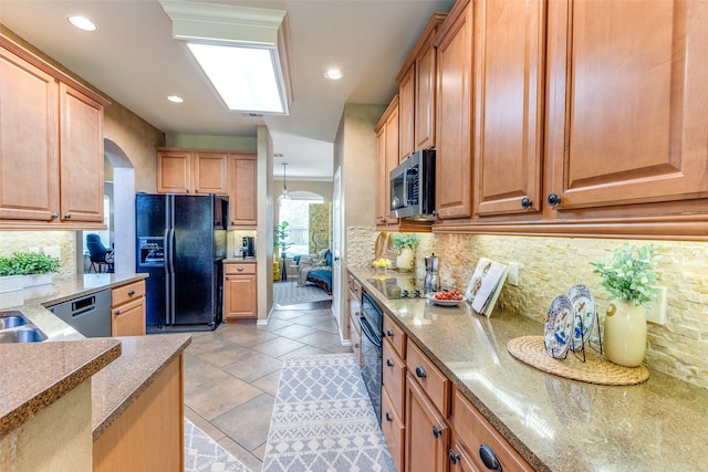 12744 Concho Dr, Frisco, TX 75033 - kitchen featuring black appliances, decorative backsplash, arched walkways, recessed lighting, and light stone countertops
