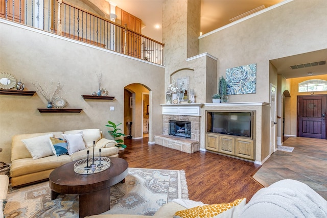 12744 Concho Dr, Frisco, TX 75033 - living area featuring arched walkways, a high ceiling, a fireplace, wood finished floors, and baseboards
