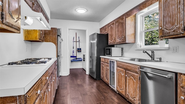 8534 Vista View Dr, Dallas, TX 75243 - kitchen featuring appliances with stainless steel finishes, under cabinet range hood, a sink, dark wood-style floors, and light countertops