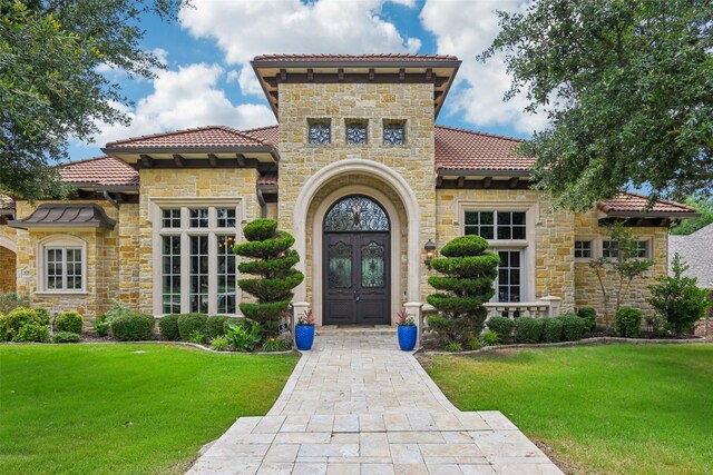6203 Sweeney Trl, Frisco, TX 75034 - property entrance featuring a tile roof, stone siding, french doors, and a yard