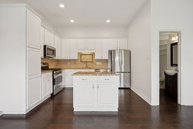 5836 Oram St, Dallas, TX 75206 - kitchen featuring appliances with stainless steel finishes, a sink, decorative backsplash, a center island, and white cabinetry