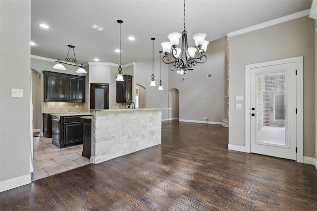209 Ellis Creek Dr, Weatherford, TX 76085 - kitchen with crown molding, wood finished floors, arched walkways, a chandelier, and backsplash