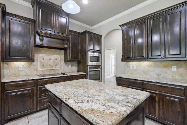 209 Ellis Creek Dr, Weatherford, TX 76085 - kitchen featuring appliances with stainless steel finishes, a center island, crown molding, decorative backsplash, and dark brown cabinets