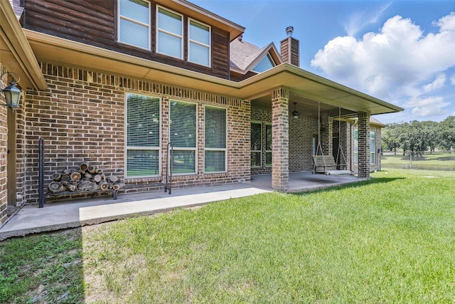 209 Ellis Creek Dr, Weatherford, TX 76085 - rear view of property featuring a chimney, brick siding, a lawn, and a patio