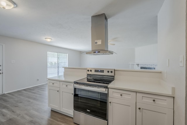 7108 Christie Ln, Dallas, TX 75249 - kitchen with electric range, island range hood, light countertops, and white cabinetry