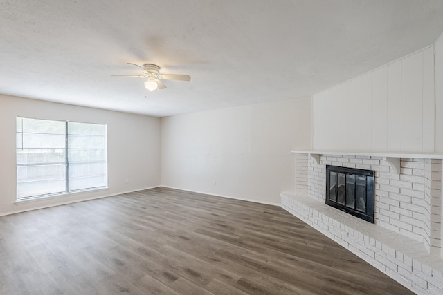 7108 Christie Ln, Dallas, TX 75249 - unfurnished living room with wood finished floors, ceiling fan, a brick fireplace, and baseboards
