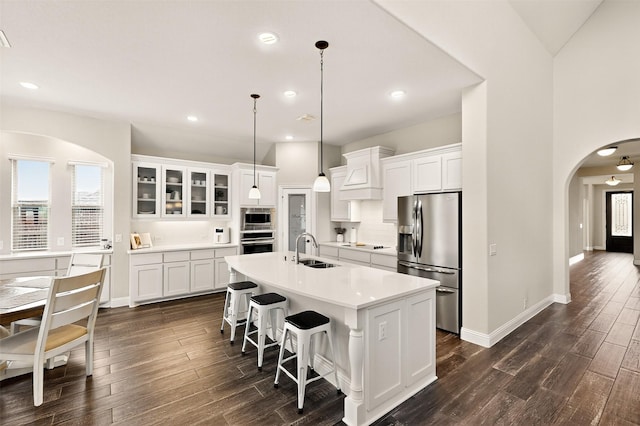 734 Oakleaf Dr, Midlothian, TX 76065 - kitchen featuring appliances with stainless steel finishes, a sink, arched walkways, dark wood-type flooring, and a kitchen island with sink