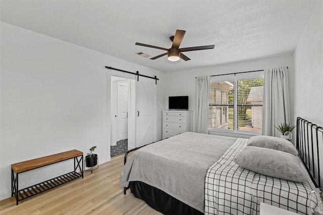 207 W River, Meridian, TX 76665 - bedroom with a barn door, light wood finished floors, and ceiling fan