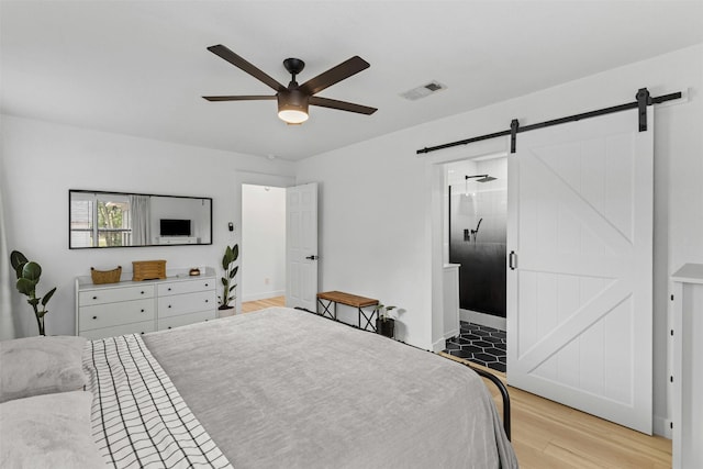 207 W River, Meridian, TX 76665 - bedroom with a barn door, light wood finished floors, ceiling fan, connected bathroom, and baseboards