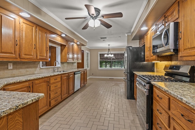 1108 Quitman St, Pittsburg, TX 75686 - kitchen featuring stainless steel appliances, a sink, a chandelier, brown cabinetry, and brick patterned floors