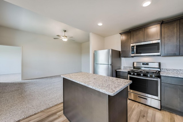1520 Woodwinds Dr, Fort Worth, TX 76140 - kitchen featuring stainless steel appliances, a kitchen island, a ceiling fan, dark brown cabinets, and light stone countertops