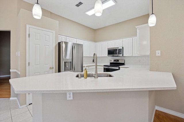 6404 Westgate Dr, North Richland Hills, TX 76182 - kitchen with stainless steel appliances, light countertops, backsplash, a peninsula, and hanging light fixtures