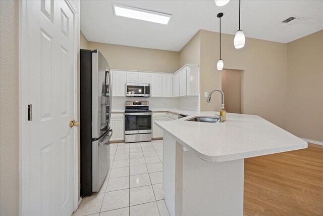 6404 Westgate Dr, North Richland Hills, TX 76182 - kitchen featuring stainless steel appliances, a peninsula, light countertops, backsplash, and white cabinets